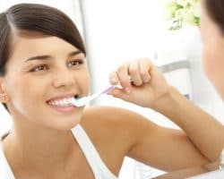 a woman looking in the mirror brushing her teeth