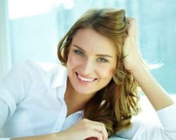 a woman smiling with a window behind her