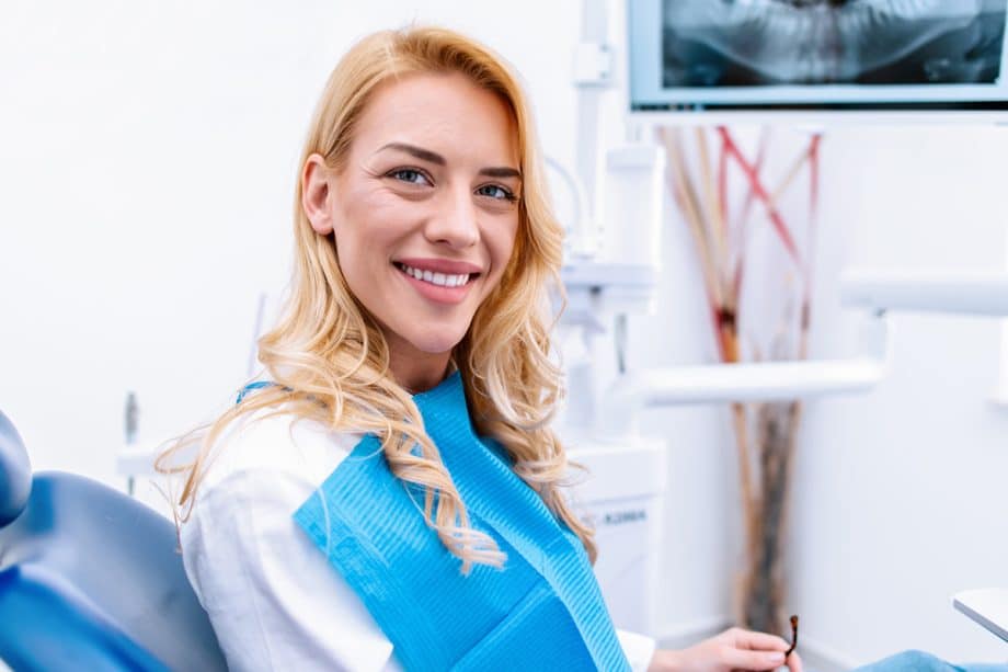 a woman in the dental exam chair smiling with her new dental veneers