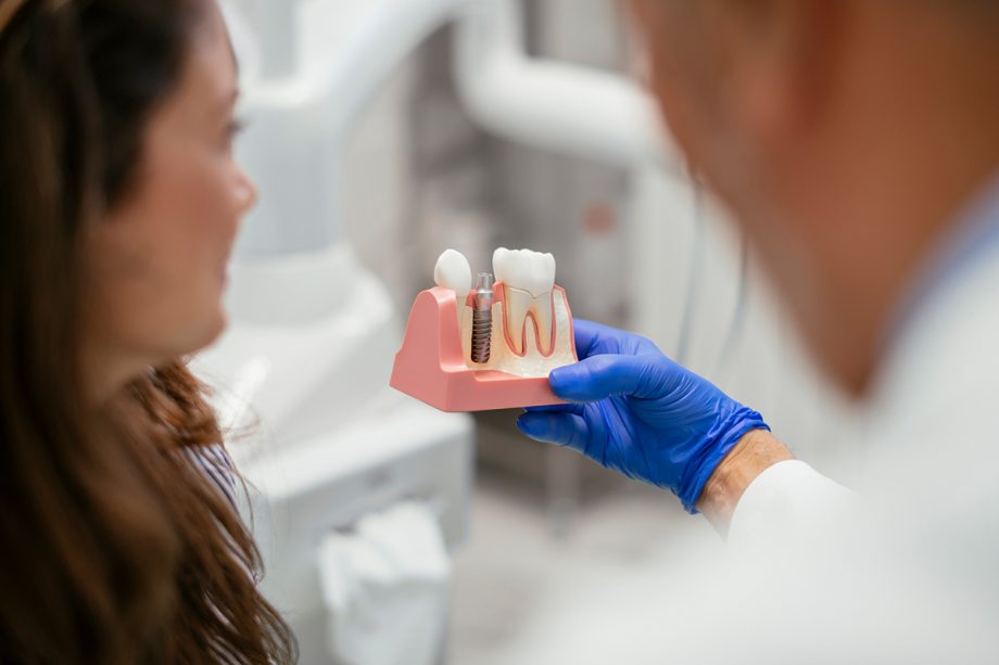 Dentist showing woman a model of dental implants