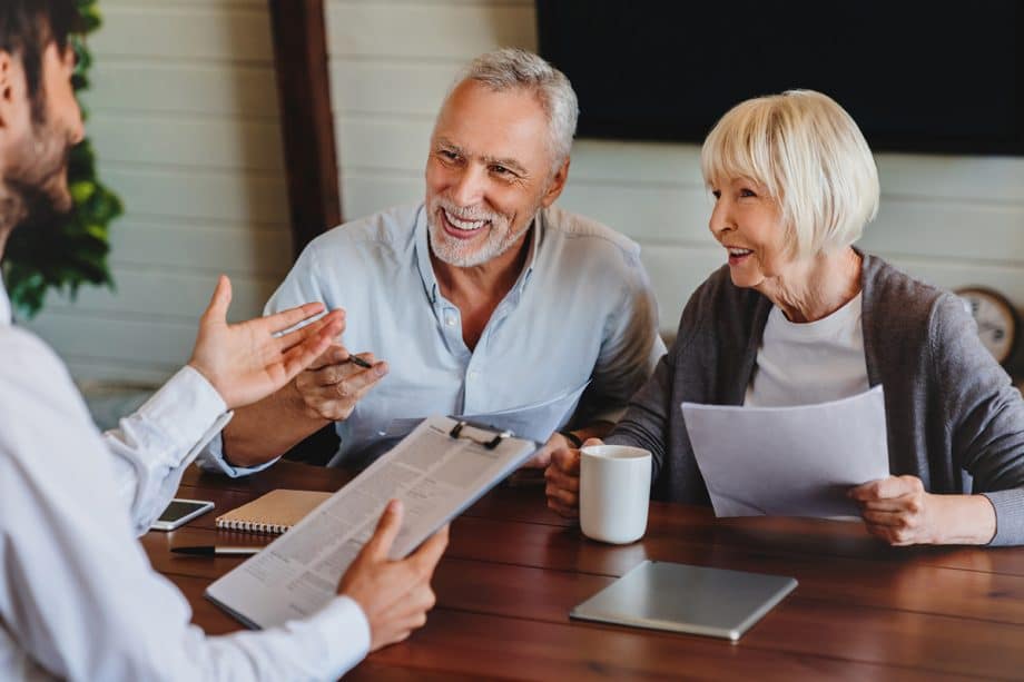 Older couple smiling and discussing paperwork with dentist